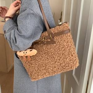 Close-up of brown teddy fleece tote bag with leather straps and toast-shaped plush charm