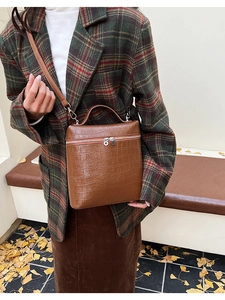 Detail of brown crocodile pattern handbag with metal zipper and fine leather strap