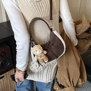 Détail d'un sac lune en daim marron avec bordure en peluche et breloque ours sur un modèle