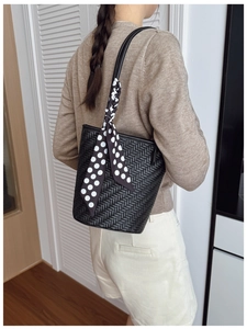 Detail of black woven shoulder bag with white polka dot scarf handle on model