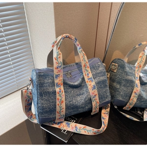 Detail of blue denim Boston bag featuring floral embroidered straps and mirror reflection