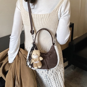Détail du sac à main marron en daim avec bordure en fourrure et breloque ourson
