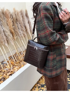 Macro view of dark brown croc-embossed leather box bag with silver zipper and handle
