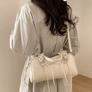 Détail du sac Boston crème avec poignées tressées et élégants glands décoratifs sur le côté