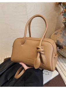 Dettaglio borsa Boston in pelle litchi marrone con patta a nodo e logo impresso