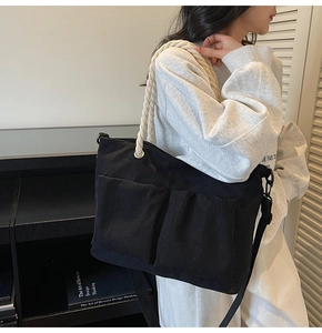Close-up of black corduroy tote bag with chunky rope handles and dual front pockets