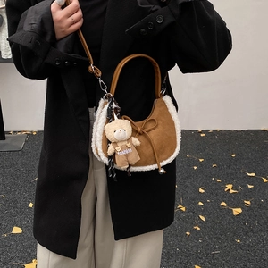 Détail d'un sac à main en daim marron avec bordure en laine et pendentif ours