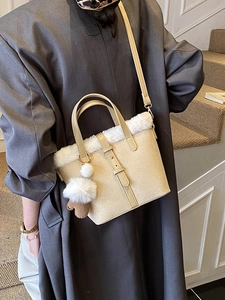 Chic cream bucket bag with faux fur trim and pom-pom charm shown on a model