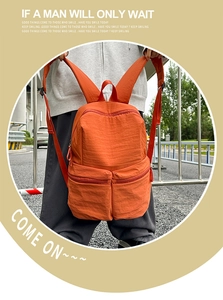 Detail view of water-resistant orange nylon backpack with front double zipper pockets