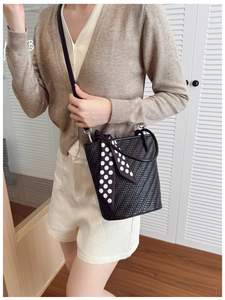 Detail of black woven bucket bag with elegant polka dot silk scarf on the handle