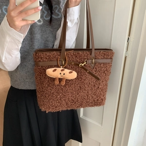 Close-up of fluffy brown tote bag with leather trim and a cute bread plush charm