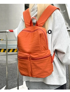 Rear view of bright orange waterproof nylon backpack with front zippered pockets