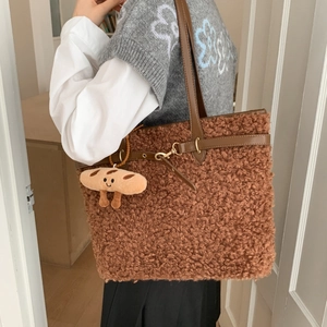 Close-up of brown plush faux shearling tote bag with leather strap and cute bread charm