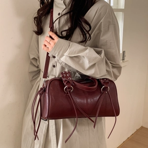 Détail du sac cylindre bordeaux avec de longues franges et un cuir mat au style vintage