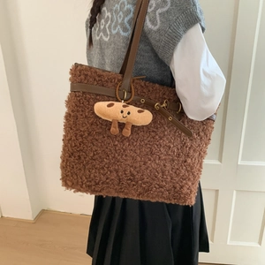 Macro detail of brown faux fur tote bag with leather strap and cute biscuit pendant charm