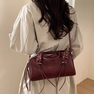 Détails du sac Boston en cuir bordeaux avec œillets décoratifs et longues franges