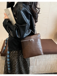 Close-up of brown crocodile pattern shoulder bag on model wearing a leather jacket