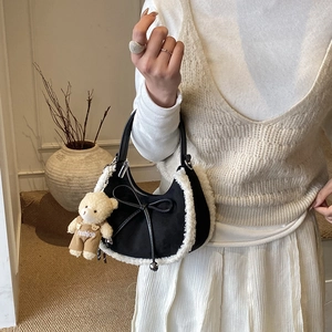 Détail du sac à main noir avec bordure en fausse fourrure blanche, nœud et ours peluche