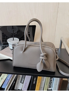 Dettaglio di una borsa quadrata in pelle taupe con scritte moda e grana fine