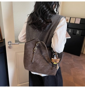 Detail of a dark brown large tote bag with teddy bear charm and sleek shoulder strap