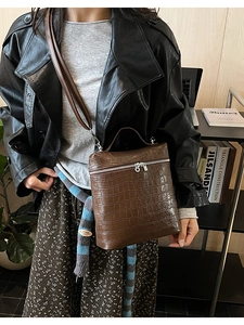 Detail of brown crocodile pattern shoulder bag with silver double zipper and handle