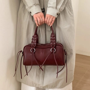 Détail du sac en cuir bordeaux avec poignée tressée et franges décoratives en cuir