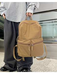 Detailed side view of a khaki nylon backpack showing the durable fabric and zipper pockets