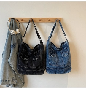 Detail view of denim tote bags in black and blue with dual utility pockets on a hook