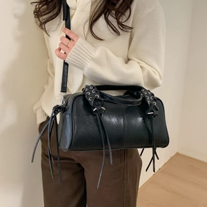 Détail du sac cabas en cuir noir avec œillets métalliques et longues franges décoratives