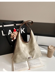 Detailed close-up of textured khaki underarm bag with a cute bear plush charm