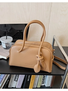 Dettaglio borsa Boston marrone in ecopelle martellata con ciondolo a nodo in stile casual