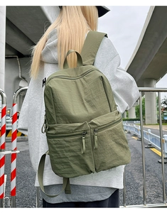 Detailed view of olive green nylon backpack texture and multi-pocket design on model