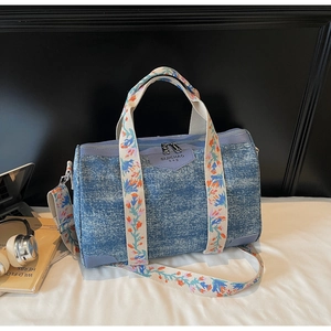 Detailed close-up of blue denim texture bag with colorful floral embroidery on handles