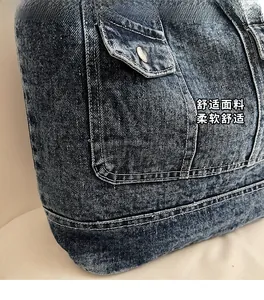 Detail of dark blue washed denim tote bag with visible stitching and metal buttons