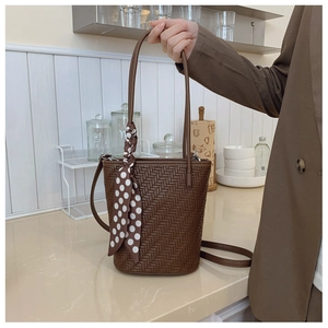 Detail of dark brown woven bucket bag with silk scarf on a bright kitchen counter