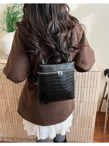 Detail showing black crocodile texture finish and silver metal zipper on a dual-use handbag