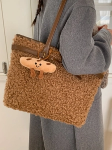 Brown teddy fleece tote bag with leather straps and cookie pendant shown on shoulder