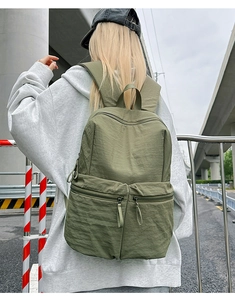 Outdoor view of an olive green large capacity nylon backpack with double front pockets