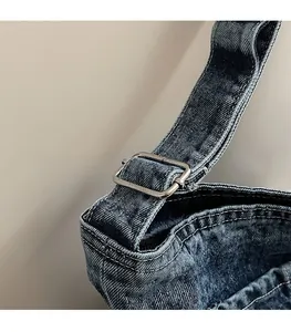 Macro shot of washed denim bag featuring adjustable metal buckle and blue textile texture