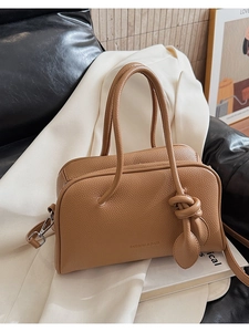 Dettaglio della pelle martellata marrone e del nodo decorativo sulla borsa a tracolla alla moda