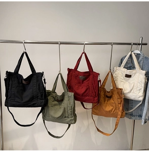 Detailed view of canvas tote bags in five colors with front pocket and fabric handles