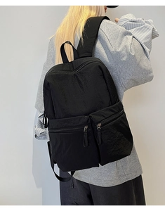 Rear view of a black nylon travel backpack on a person with multiple zipper pockets