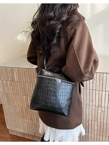 Detail of black crocodile texture shoulder bag with metallic zipper and trapezoid design