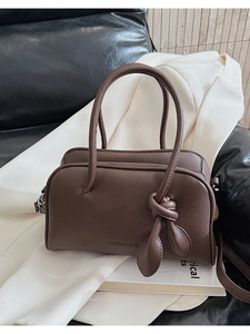 Dettaglio della borsa Boston in pelle marrone caffè con motivo litchi e ciondolo a nodo