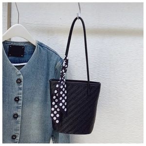 Close-up of black woven shoulder bag with a stylish polka dot scarf on the handle