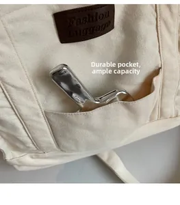 Detail of canvas tote bag front pocket with leather logo tag and spacious storage