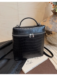 Detail of black crocodile embossed handbag with silver zipper and premium leather texture