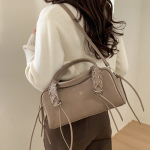 Détail du sac cabas en cuir kaki avec poignée tressée et pompon porté à l'épaule