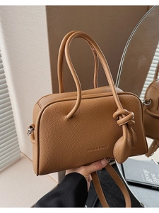 Dettaglio della borsa squadrata in pelle marrone con motivo litchi e fibbie in metallo
