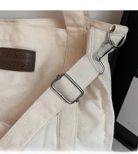 Detail of adjustable canvas strap with silver metal buckle and brown leather fashion tag